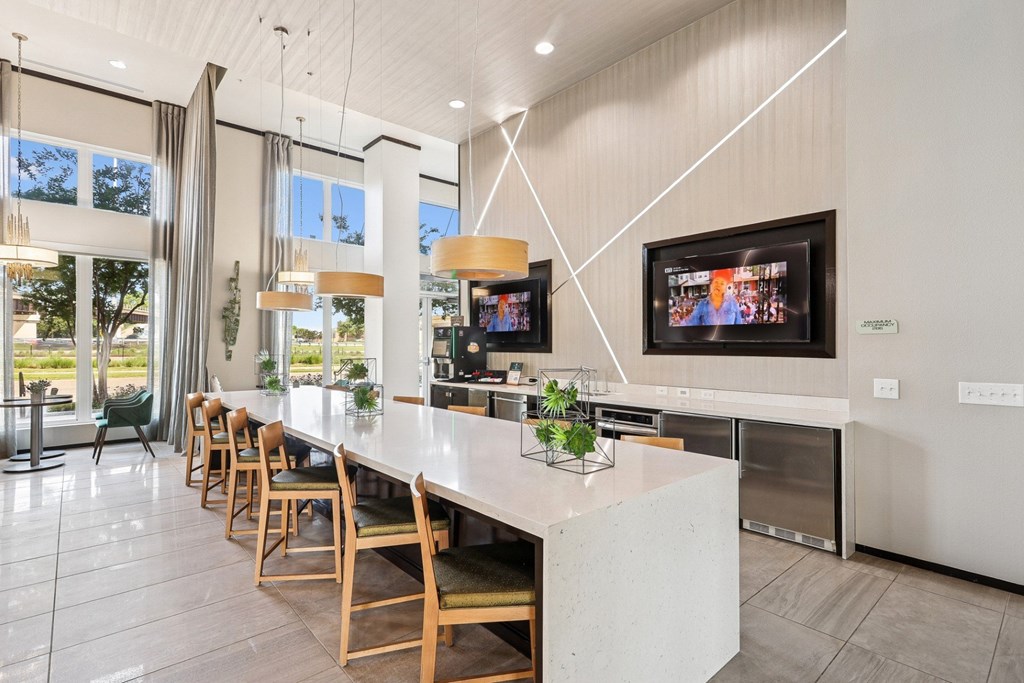 Clubhouse kitchen with a long island and wooden chairs at GreenVue apartments in Richardson, TX