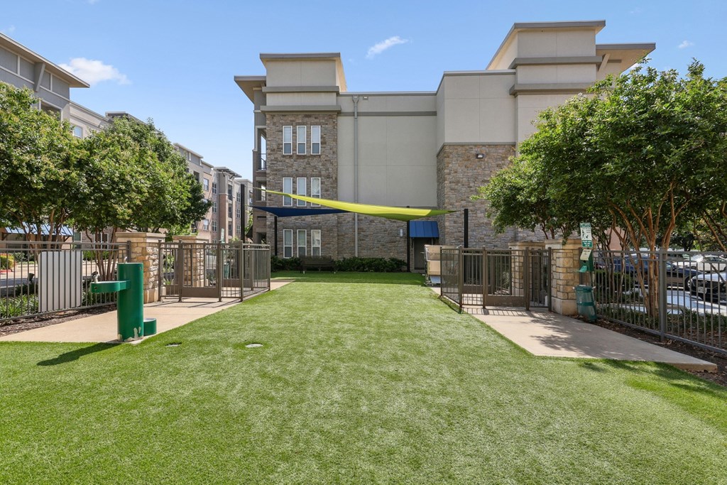 Dog park with a large grassy area and water fountain at GreenVue apartments in Richardson, TX