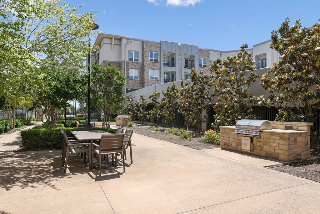 A courtyard with a table and chairs and grilling station at GreenVue apartments in Richardson, TX