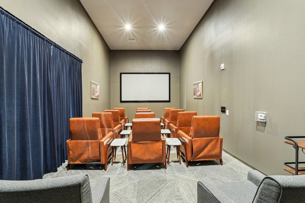 Movie room with theatre style chairs and a projector screen at GreenVue apartments in Richardson, TX