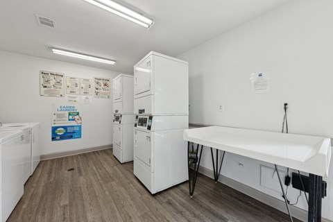 A laundry room with washers, dryers, and a folding counter at Gwinnett Square Apartments in Duluth, GA