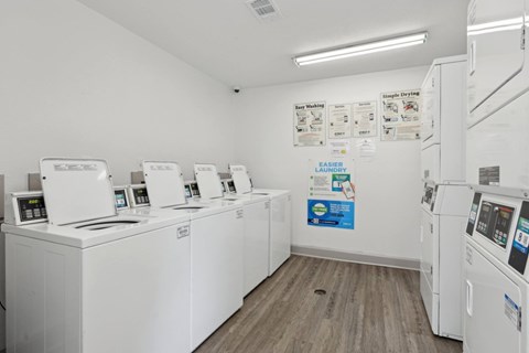 A laundry center with a row of washing machines and dryers at Gwinnett Square Apartments in Duluth, GA