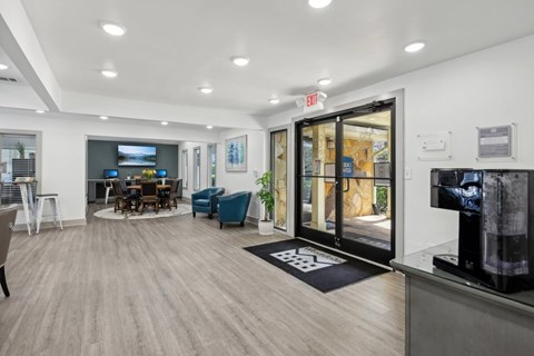 A leasing office with a coffee machine, chairs, and tables at Gwinnett Square Apartments in Duluth, GA