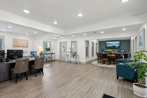 A modern leasing office with a wood floor and desks and chairs at Gwinnett Square Apartments in Duluth, GA