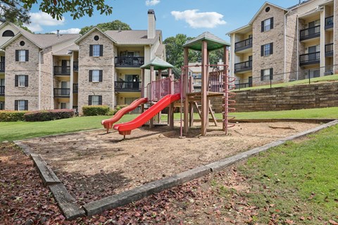 A red playground with apartment buildings in the background at Gwinnett Square Apartments in Duluth, GA