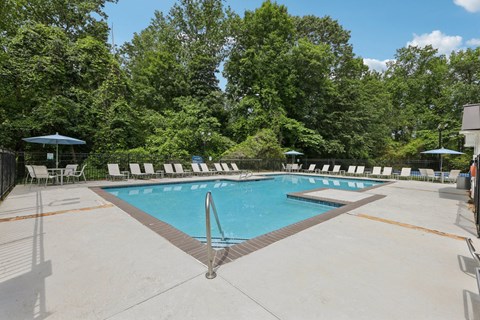 A swimming pool with white lounge chairs around it at Gwinnett Square Apartments in Duluth, GA