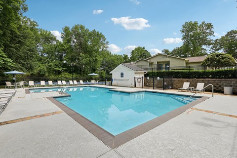 A large swimming pool surrounded by a fence and trees at Gwinnett Square Apartments in Duluth, GA