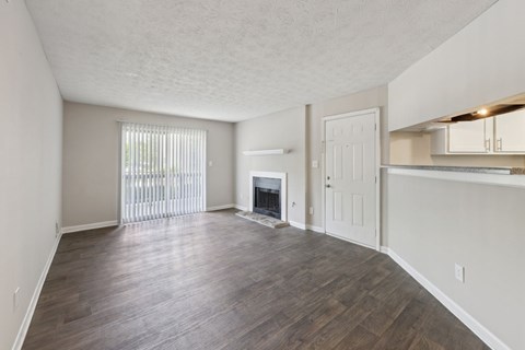 A living room with a fireplace and wooden floors at Gwinnett Square Apartments in Duluth, GA