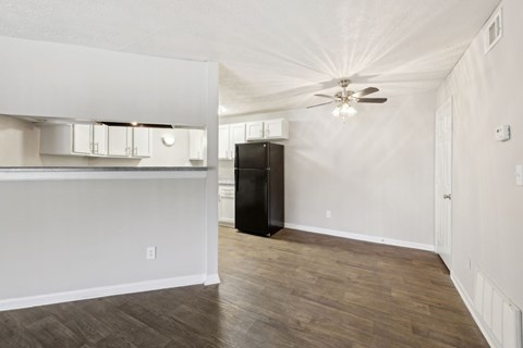 A dining room with a ceiling fan leading into the kitchen at Gwinnett Square Apartments in Duluth, GA