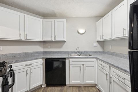 A kitchen with white cabinets and black appliances at Gwinnett Square Apartments in Duluth, GA