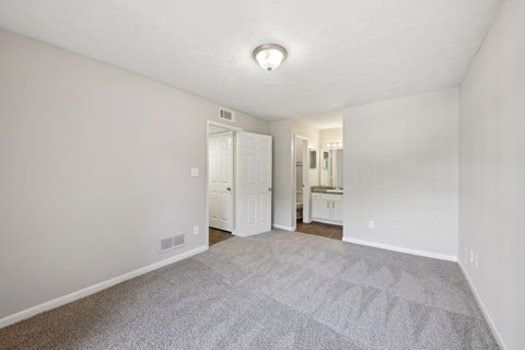 A bedroom with carpet leading to a bathroom and closet  at Gwinnett Square Apartments in Duluth, GA