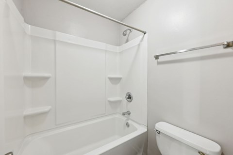 A white bathroom with a tub and toilet at Gwinnett Square Apartments in Duluth, GA