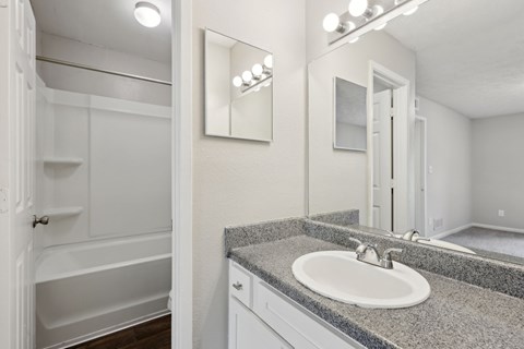 A bathroom with a sink, mirror, and a bathtub at Gwinnett Square Apartments in Duluth, GA