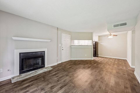A living room with a fireplace that leads into the dining and kitchen area at Gwinnett Square Apartments in Duluth, GA