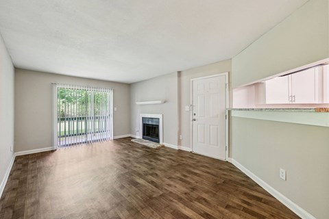 A living room with a fireplace and a glass door leading to a balcony at Gwinnett Square Apartments in Duluth, GA