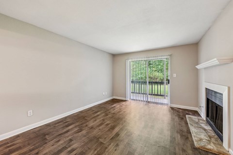 A living room with a fireplace and a sliding glass door leading to a balcony at Gwinnett Square Apartments in Duluth, GA