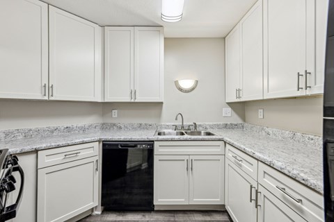 A kitchen with white cabinets and a black dishwasher at Gwinnett Square Apartments in Duluth, GA