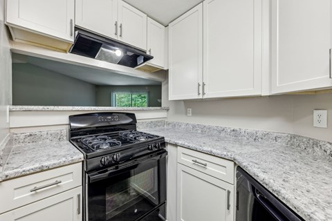 A kitchen with a black stove top oven and white cabinets at Gwinnett Square Apartments in Duluth, GA