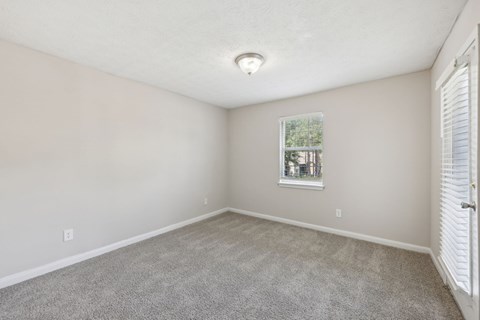 A carpeted bedroom with a window at Gwinnett Square Apartments in Duluth, GA