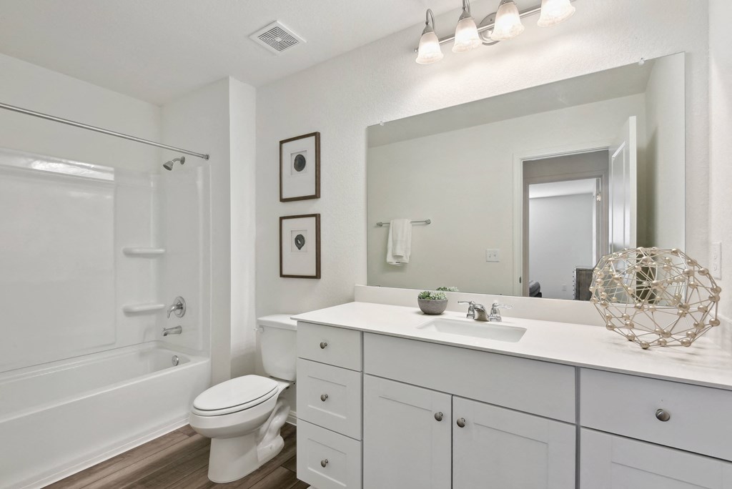 a bathroom with a large mirror and a toilet next to a bathtub