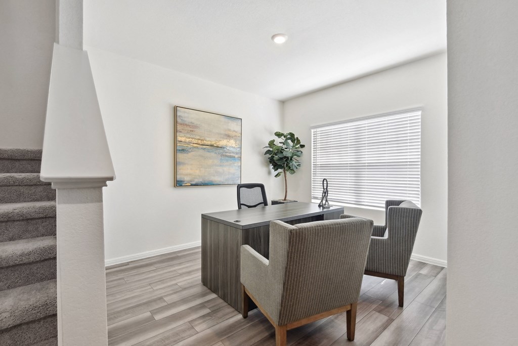 a home office with white walls and hardwood flooring