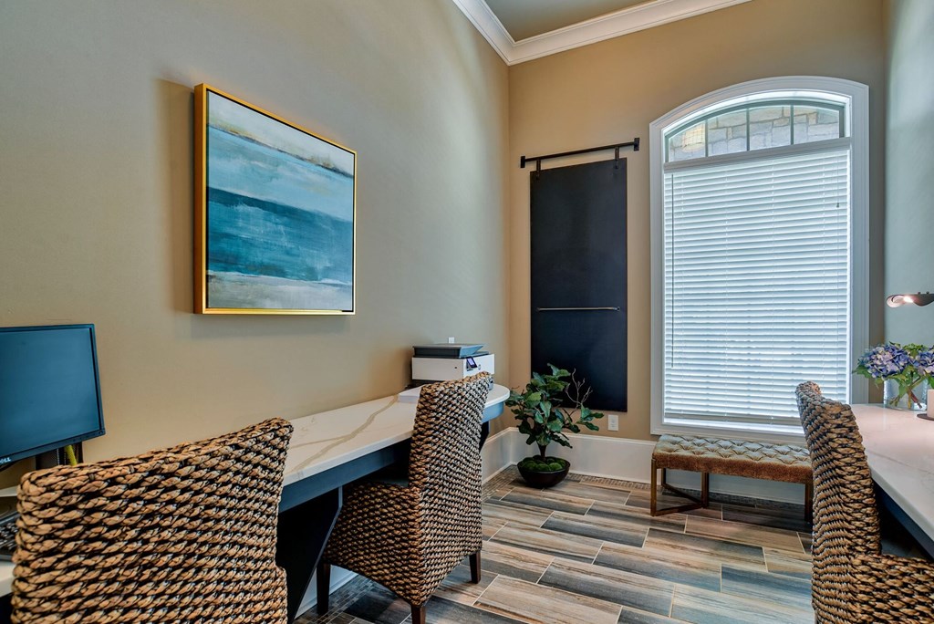 a home office with a desk and chairs and a window