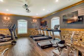 a gym with treadmills and a tv on the wall