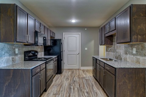 a kitchen with dark cabinets and granite counter tops and a door