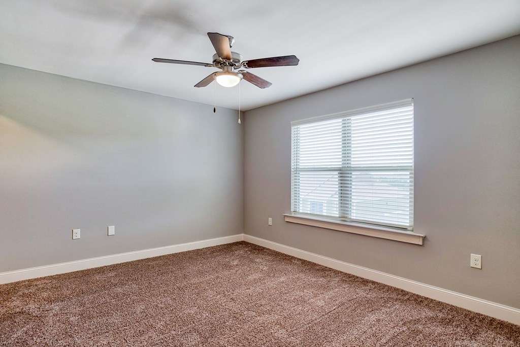 an empty bedroom with a ceiling fan and a window