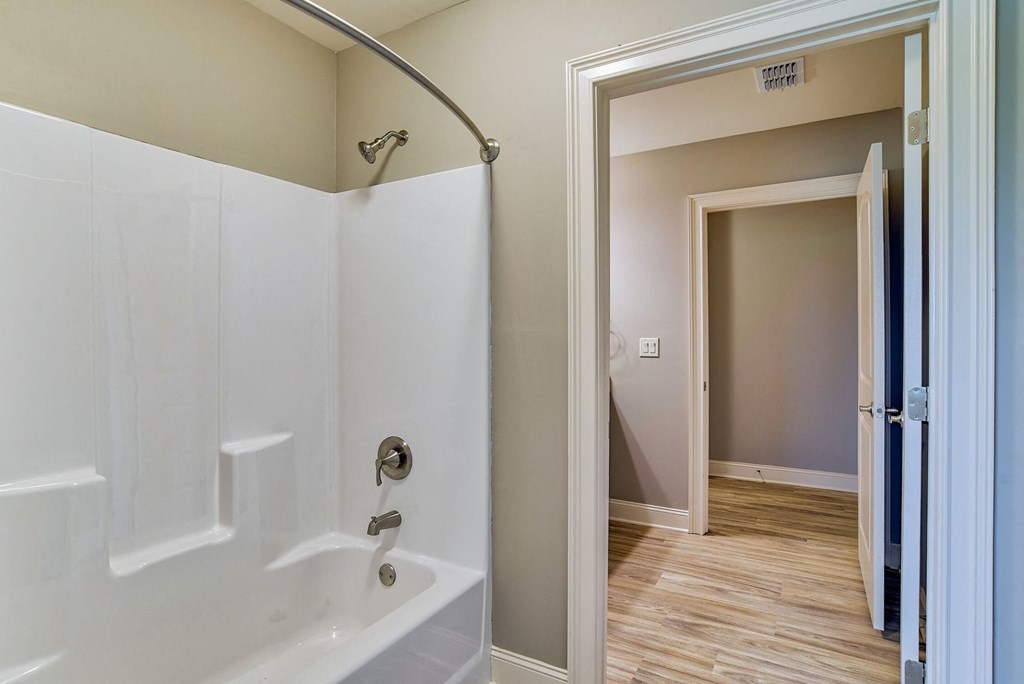 a bathroom with a shower and a door to a hallway