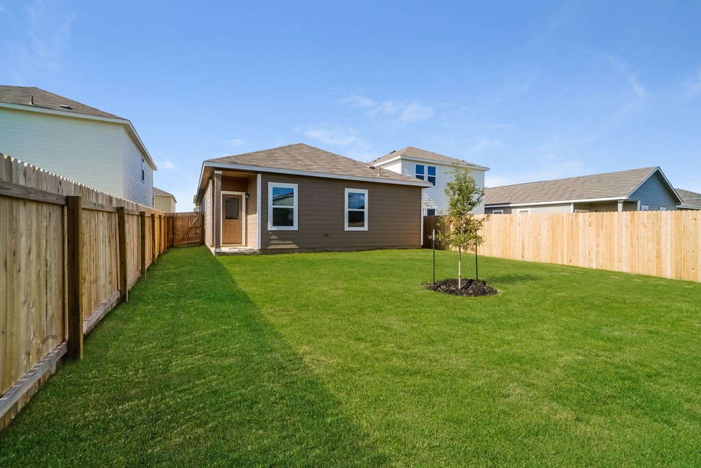 a backyard with green grass and a wooden fence at Beacon at Meridian, Texas