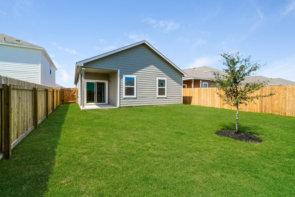 a backyard with a green lawn and a gray house at Beacon at Meridian, San Antonio Texas