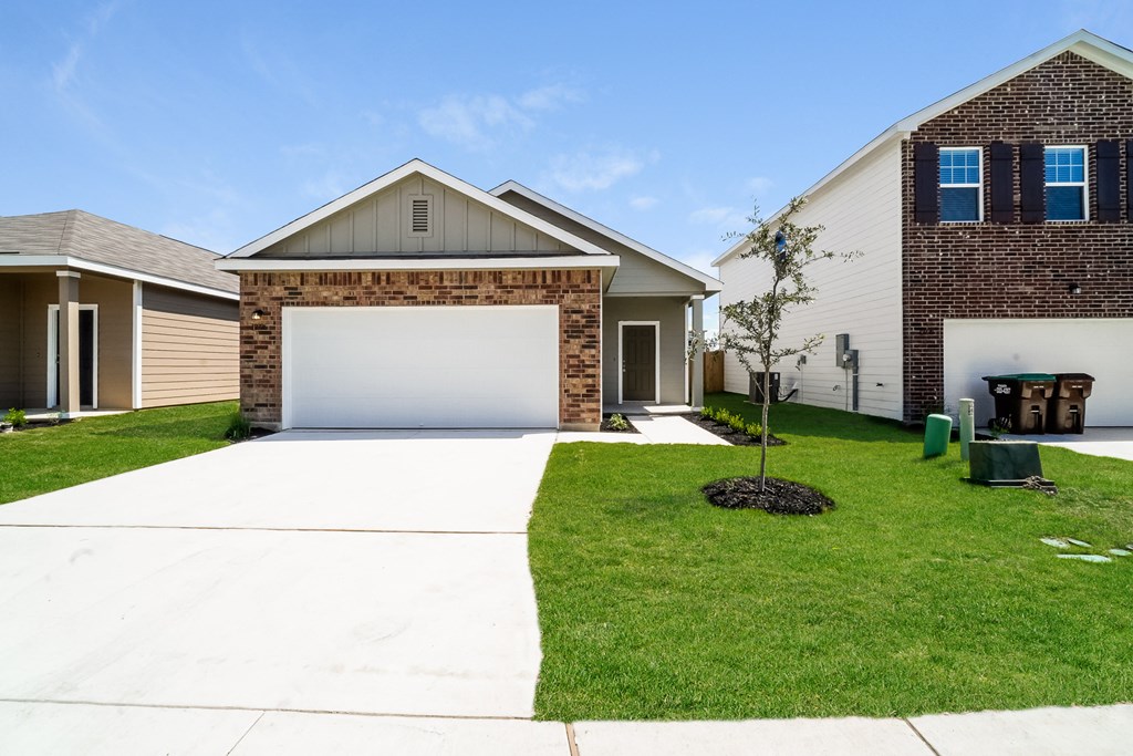 a house with a white garage door in front of a green lawn at Beacon at Meridian, San Antonio