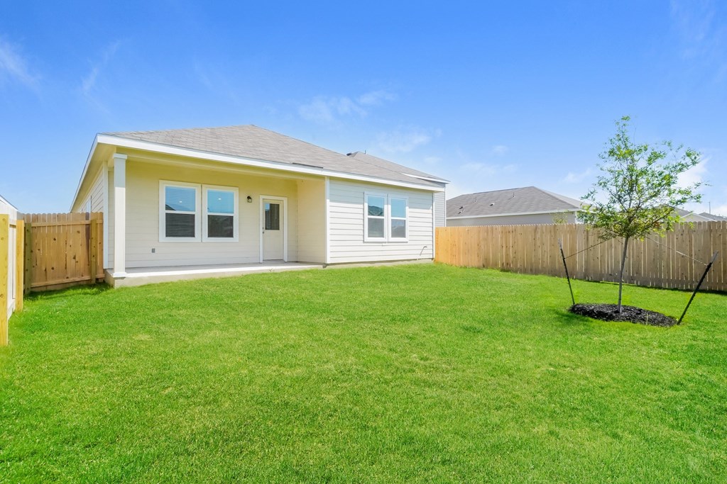 a backyard with green grass and a white house in the background at Beacon at Meridian, San Antonio, TX