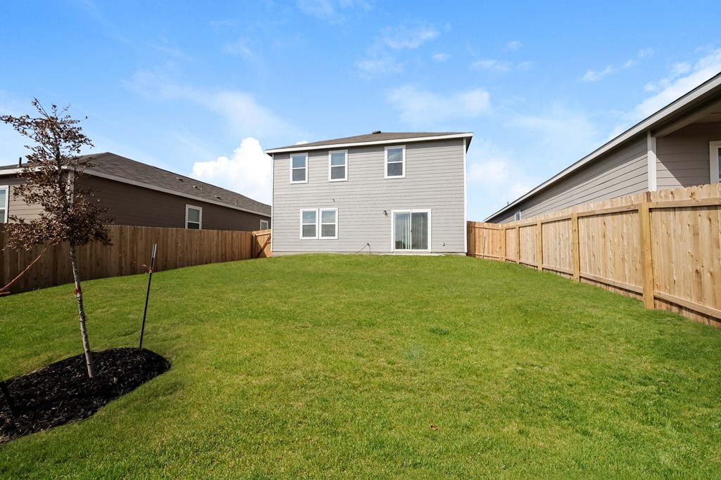 a backyard with a large lawn and a house in the background at Beacon at Meridian, San Antonio, TX 78245