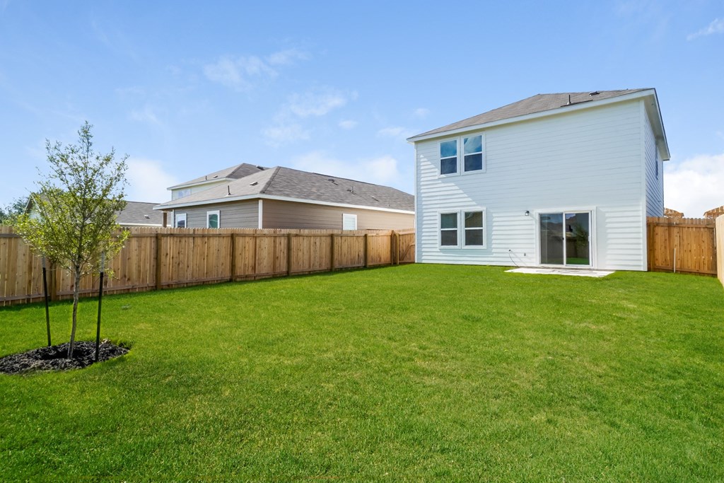 a backyard with green grass and a white house with a gray roof at Beacon at Meridian, San Antonio