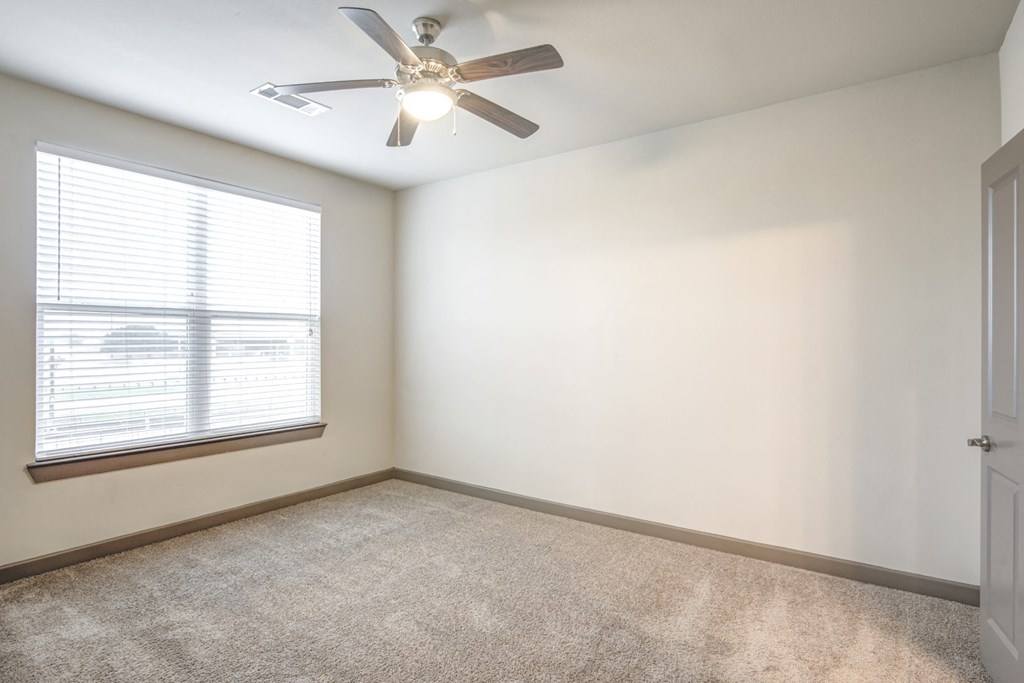 an empty room with a ceiling fan and a window