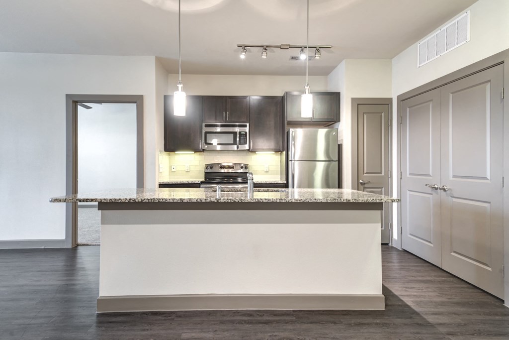 an empty kitchen with a large island with a granite counter top