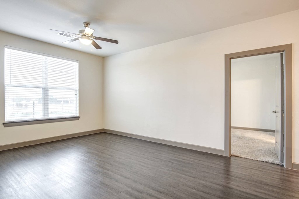 an empty living room with a window and a ceiling fan