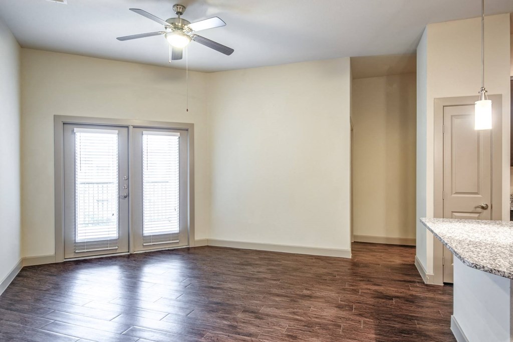 an empty living room with white walls and a ceiling fan