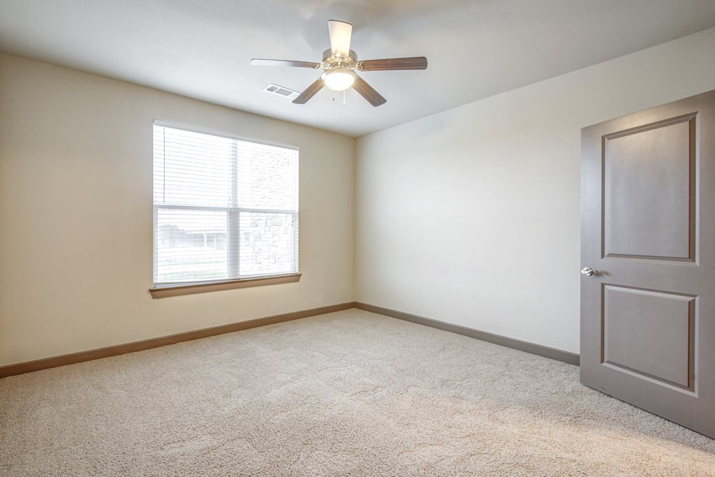 an empty room with a ceiling fan and a window