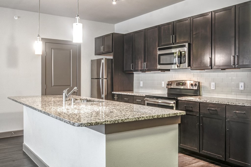a kitchen with a marble counter top and black cabinets