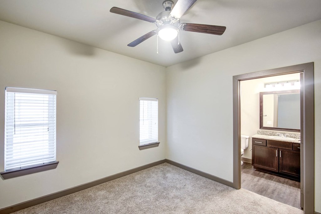 an empty bedroom with a ceiling fan and a mirror