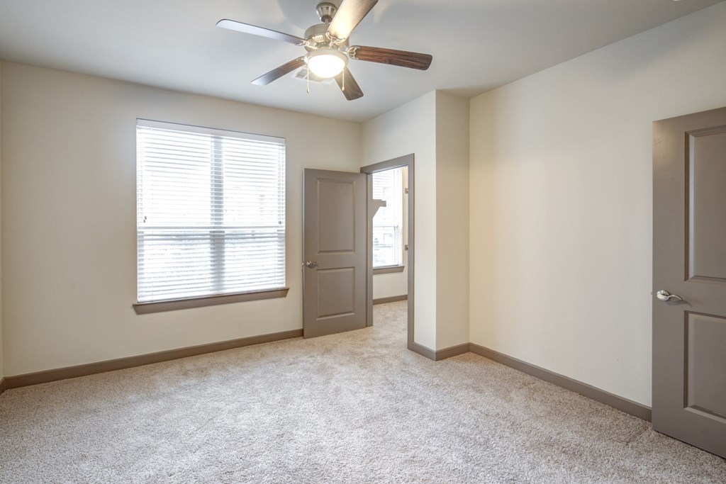 an empty living room with a ceiling fan and a window