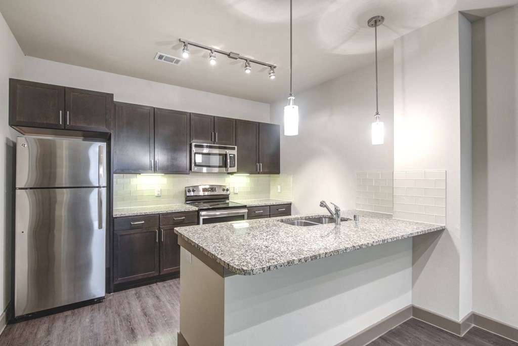 a kitchen with a granite counter top and stainless steel refrigerator