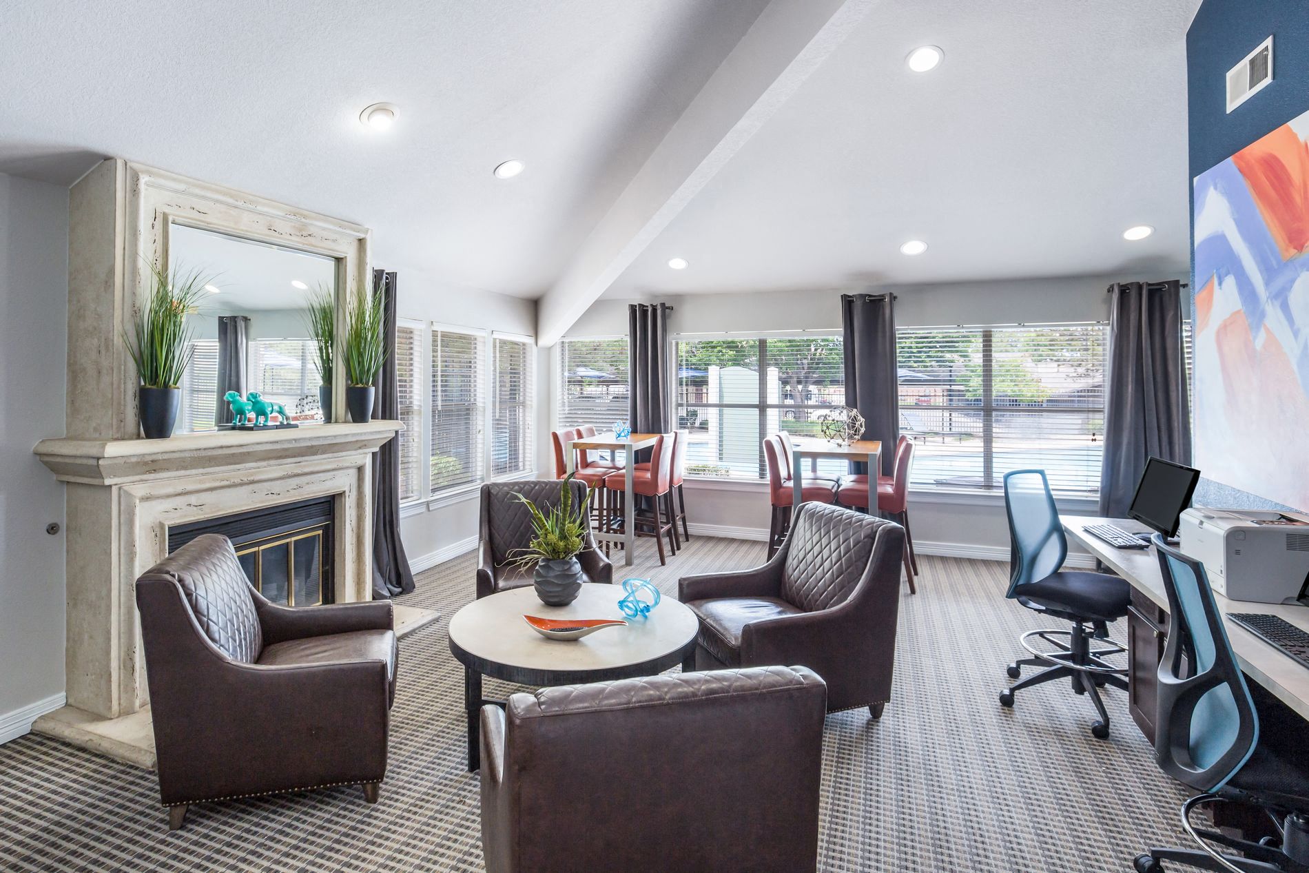 a living room with chairs and a desk and a fireplace