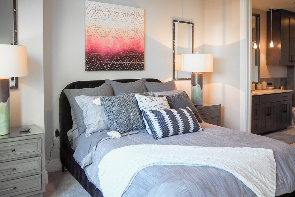 3 bedroom model third bedroom viewing a bed with pillows and a painting on the wall at The Hamilton apartments in Dallas, TX