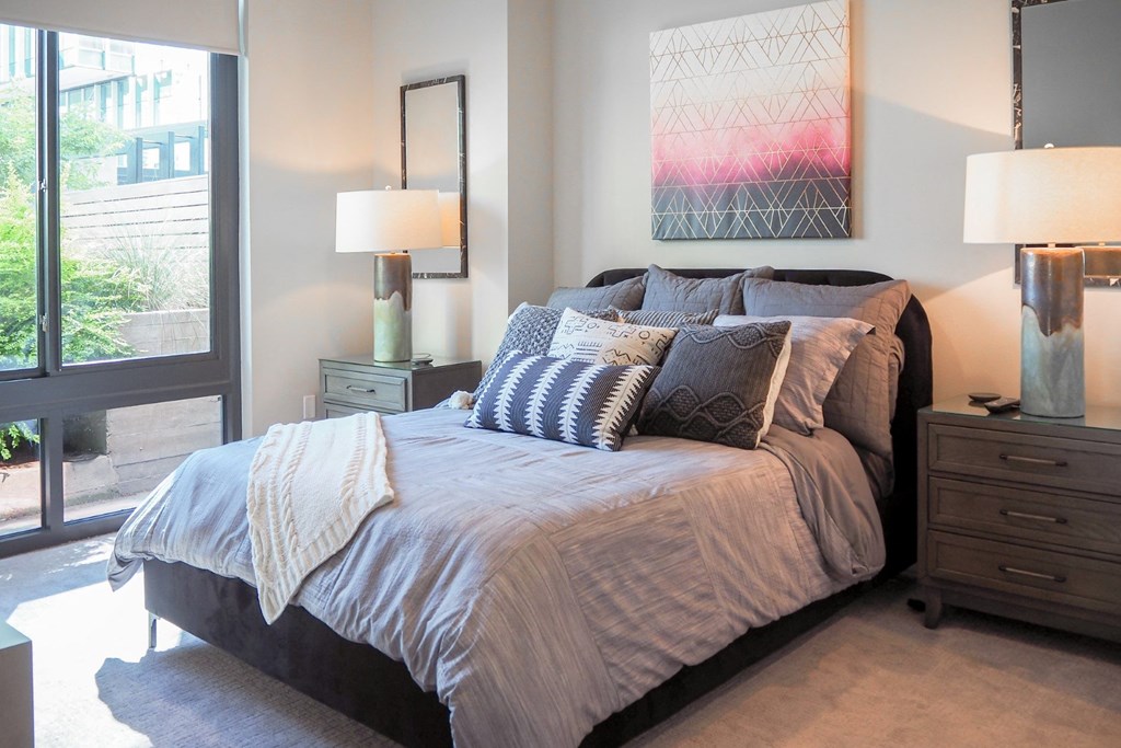 3 bedroom model bedroom with a bed and a big window at The Hamilton apartments in Dallas, TX