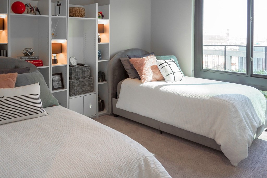 3 bedroom model second bedroom with two twin size beds and a bookcase at The Hamilton apartments in Dallas, TX