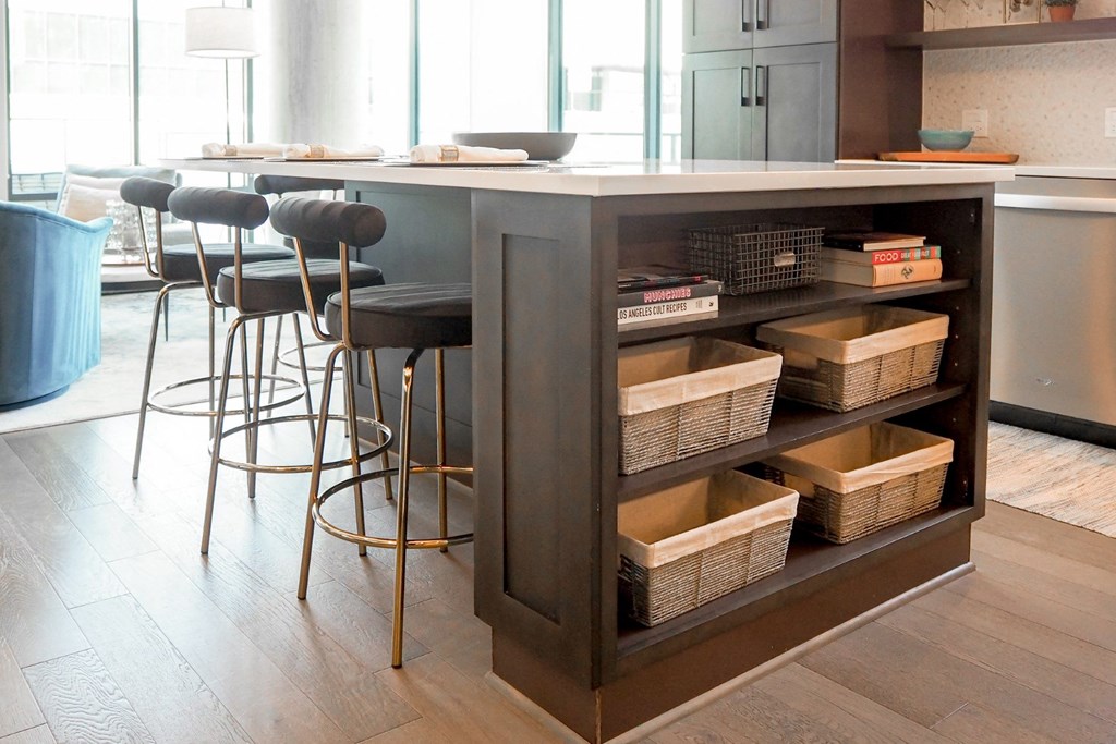 3-Bedroom model kitchen island with wicker baskets on the side and some stools at The Hamilton apartments in Dallas, TX